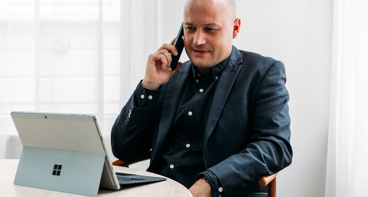 Sales consultant on a client call reviewing quote conversion rates on a laptop