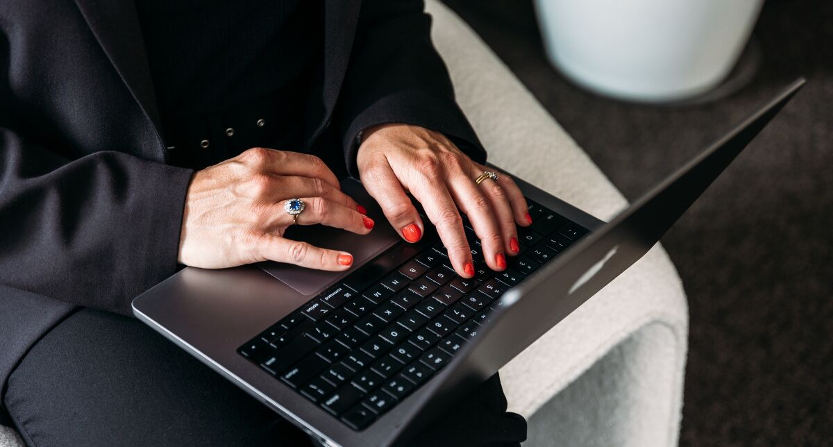 Hands typing on a laptop, updating sales and marketing notes between client conversations